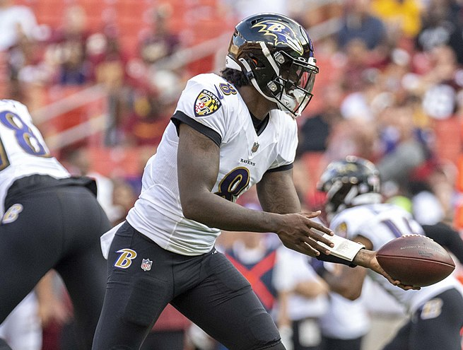 Baltimore Ravensin pelinrakentaja Lamar Jackson ojentaa palloa.
