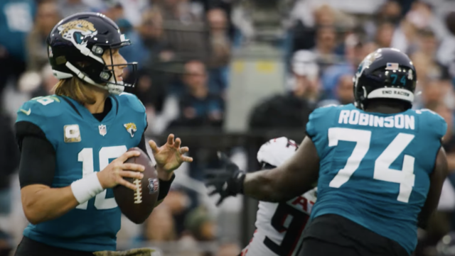 Kuvassa Jacksonville Jaguarsin pelinrakentaja Trevor Lawrence etsii syötön kohdetta, kun linjamies Cam Robinson blokkaa.